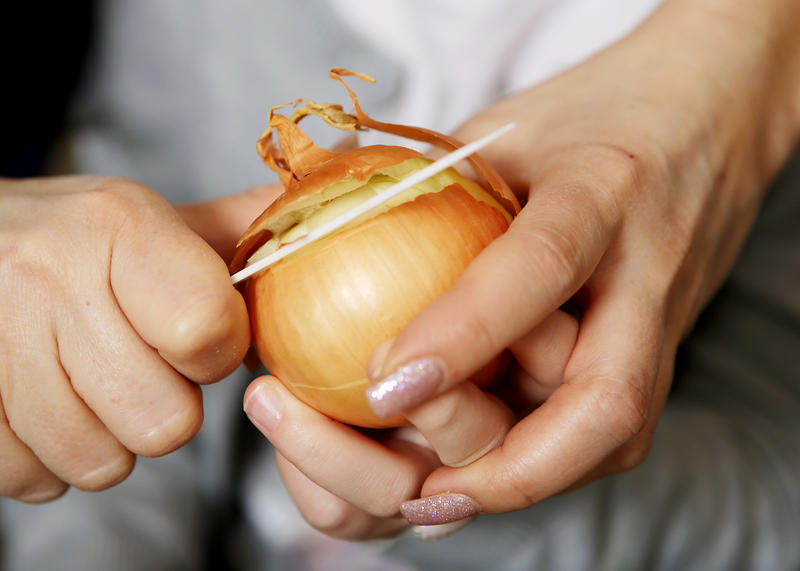 s:42:"Eine Zwiebel wird für ein Essen geschält";